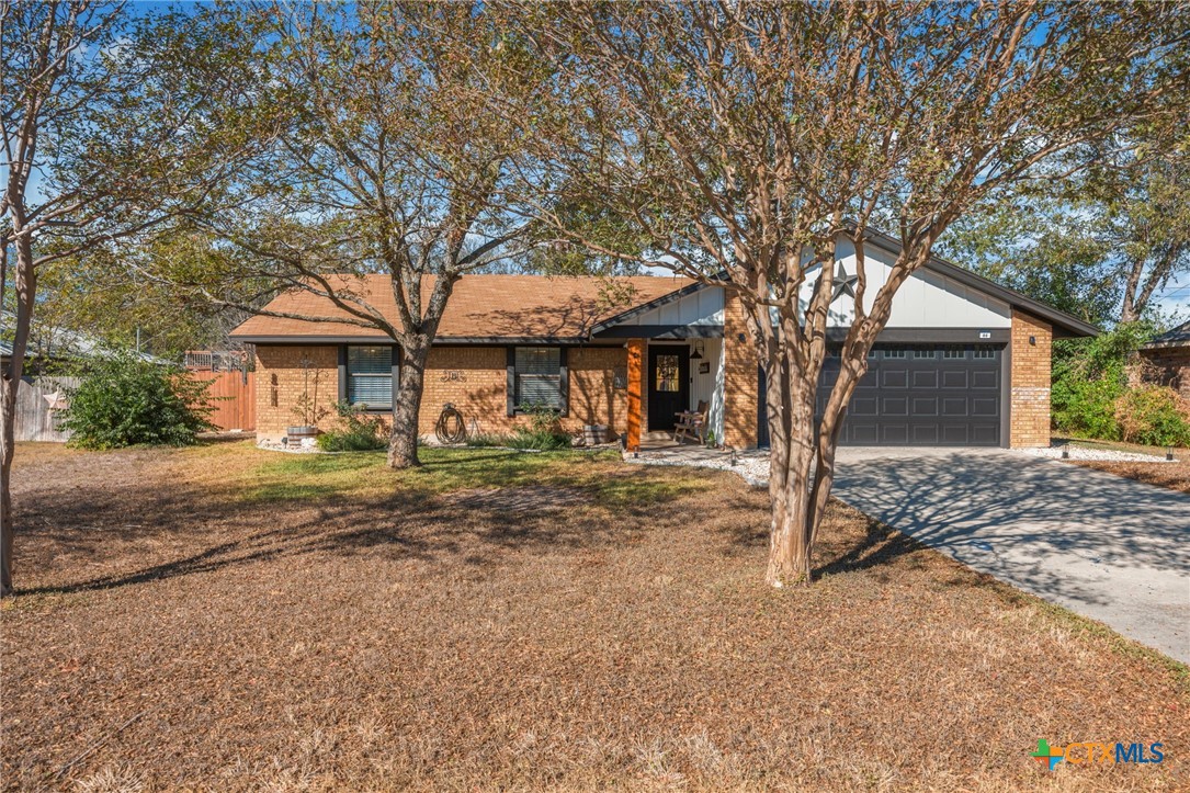 a front view of a house with a dirt yard and a large tree