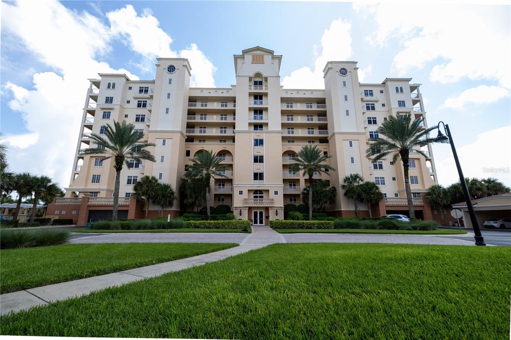 a front view of multi story residential apartment building with yard and trees