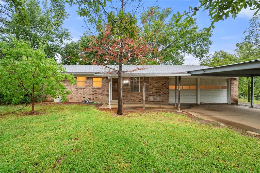 Ranch-style house with a garage, a carport, and a front lawn