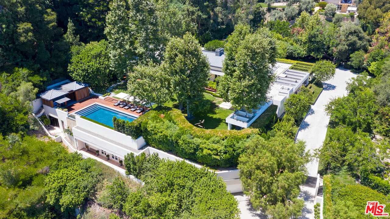 an aerial view of residential house with outdoor space and trees all around