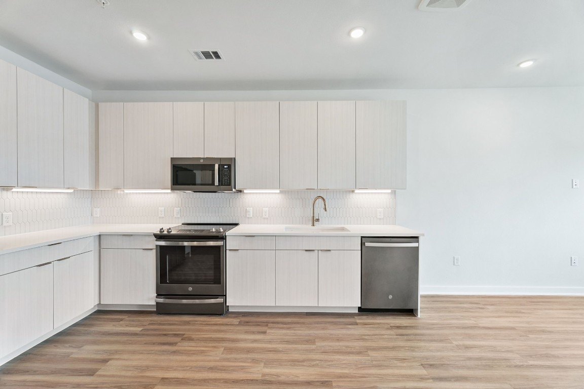 a kitchen with stainless steel appliances a stove top oven and white cabinets