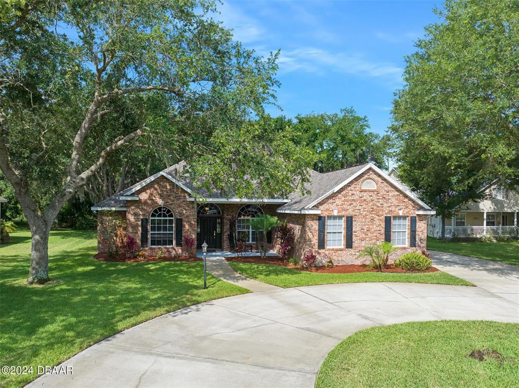 a view of a house with a big yard plants and large trees