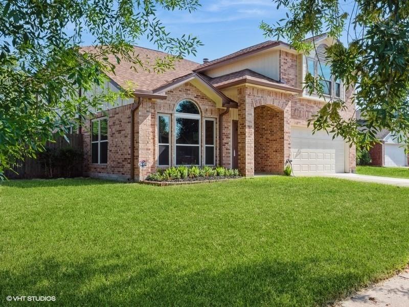 This is a single-story brick home featuring an arched entryway, large windows, and an attached two-car garage, set on a well-maintained lawn.