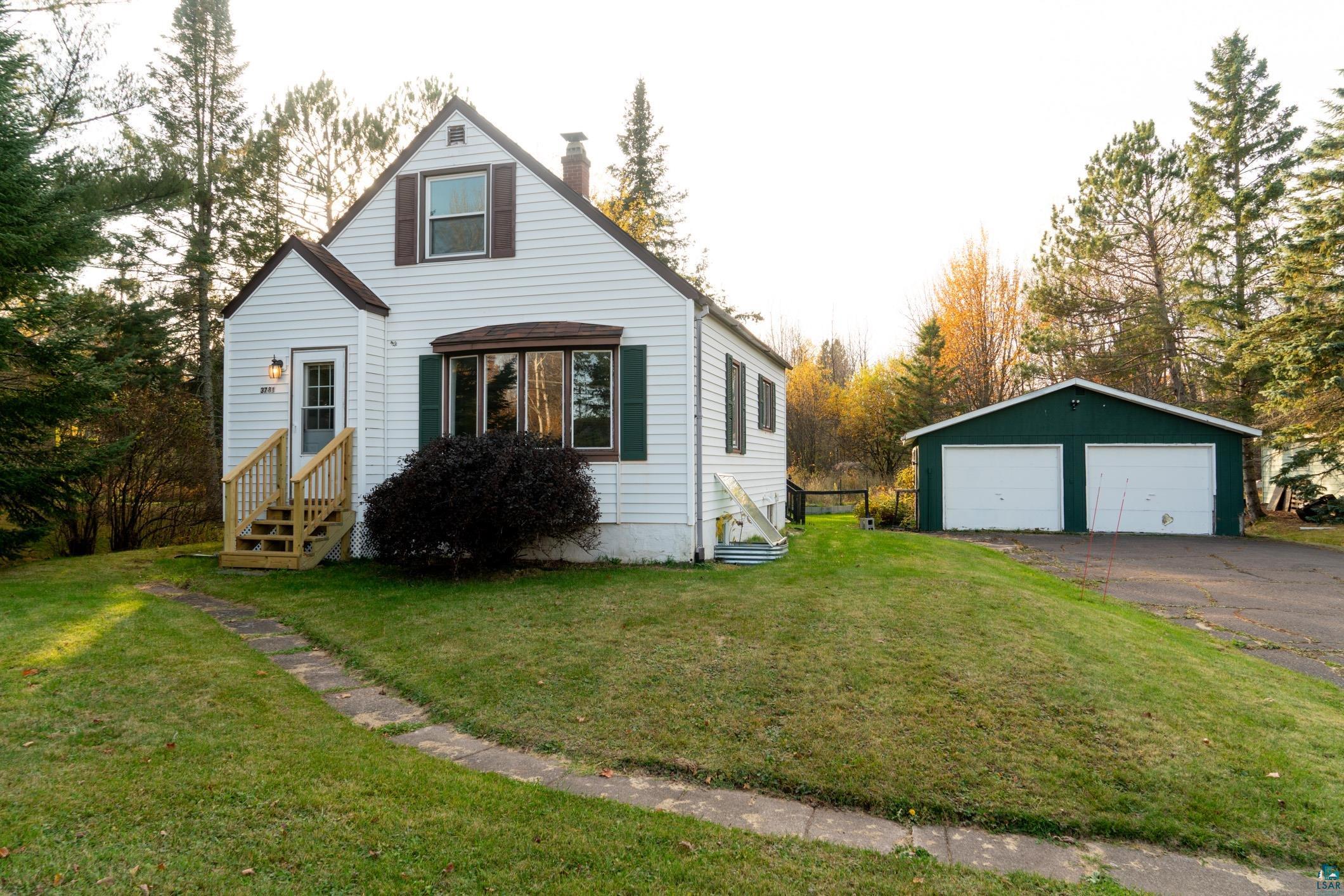 View of front of property featuring a garage, an outdoor structure, and a front lawn