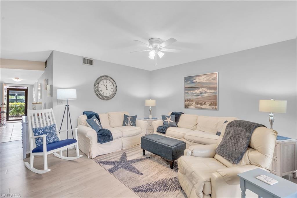 a living room with furniture a clock on wall and a window