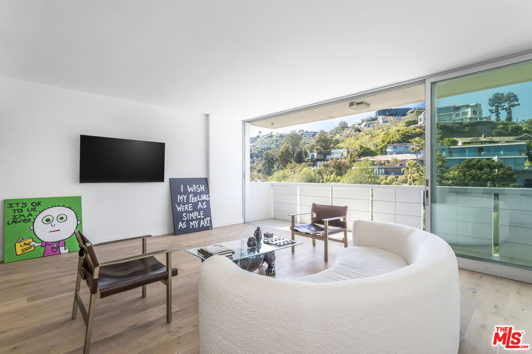 a living room with furniture a flat screen tv and a floor to ceiling window