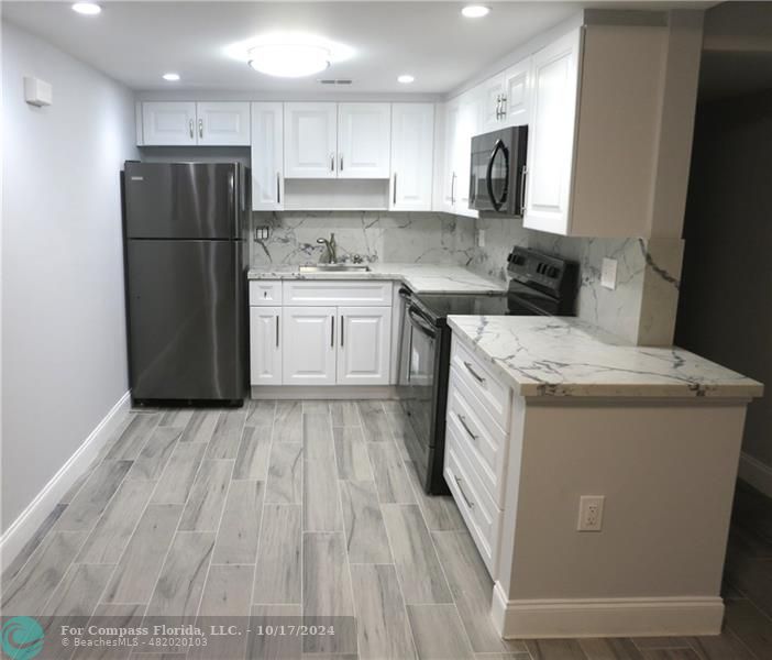 a kitchen with a refrigerator a stove top oven a sink and cabinets