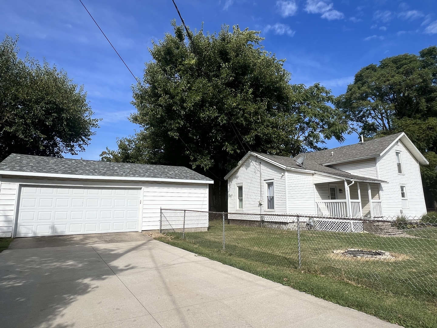 a view of a yard in front of a house with plants and large tree