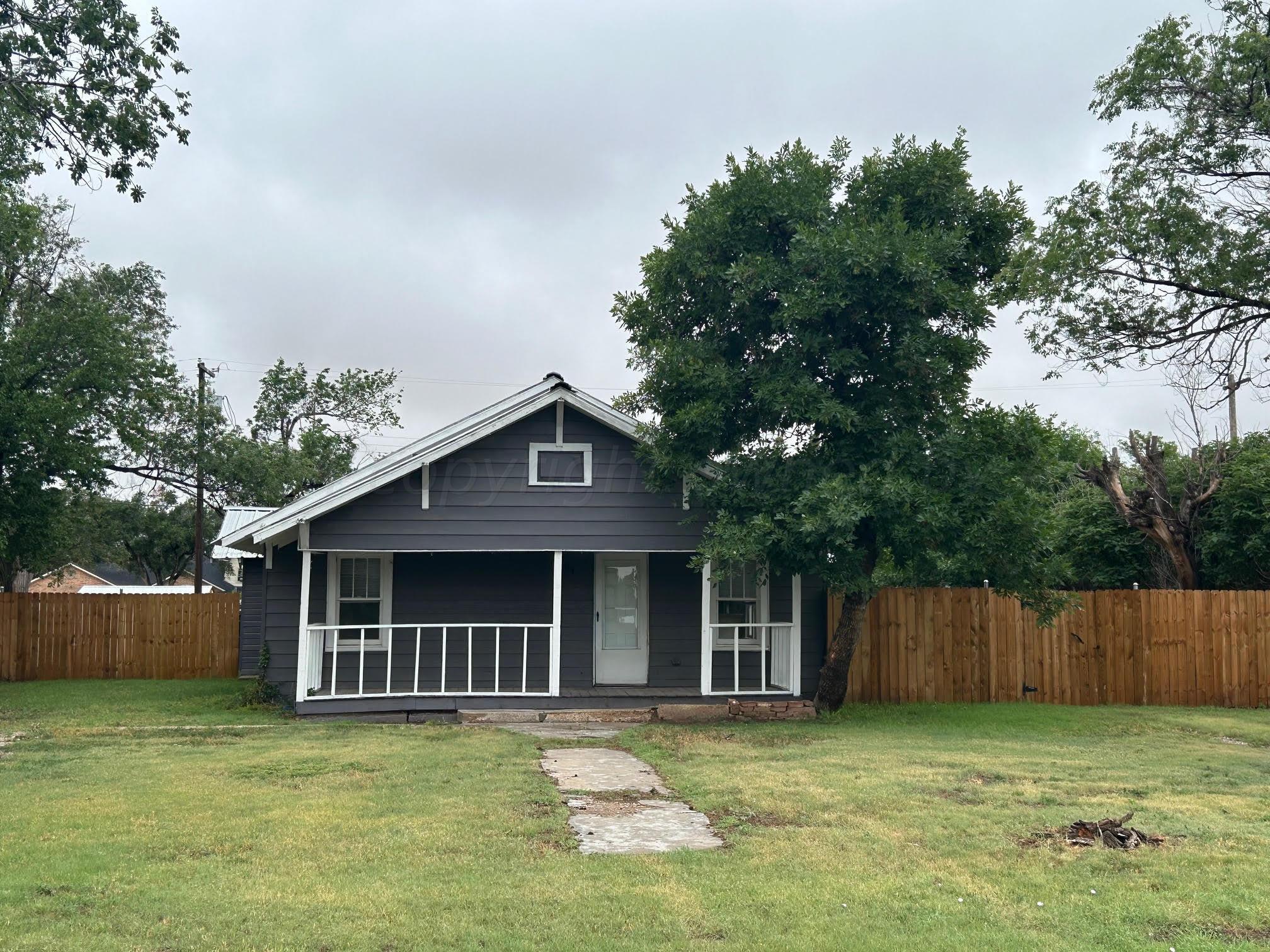 a view of a house with a yard and a large tree