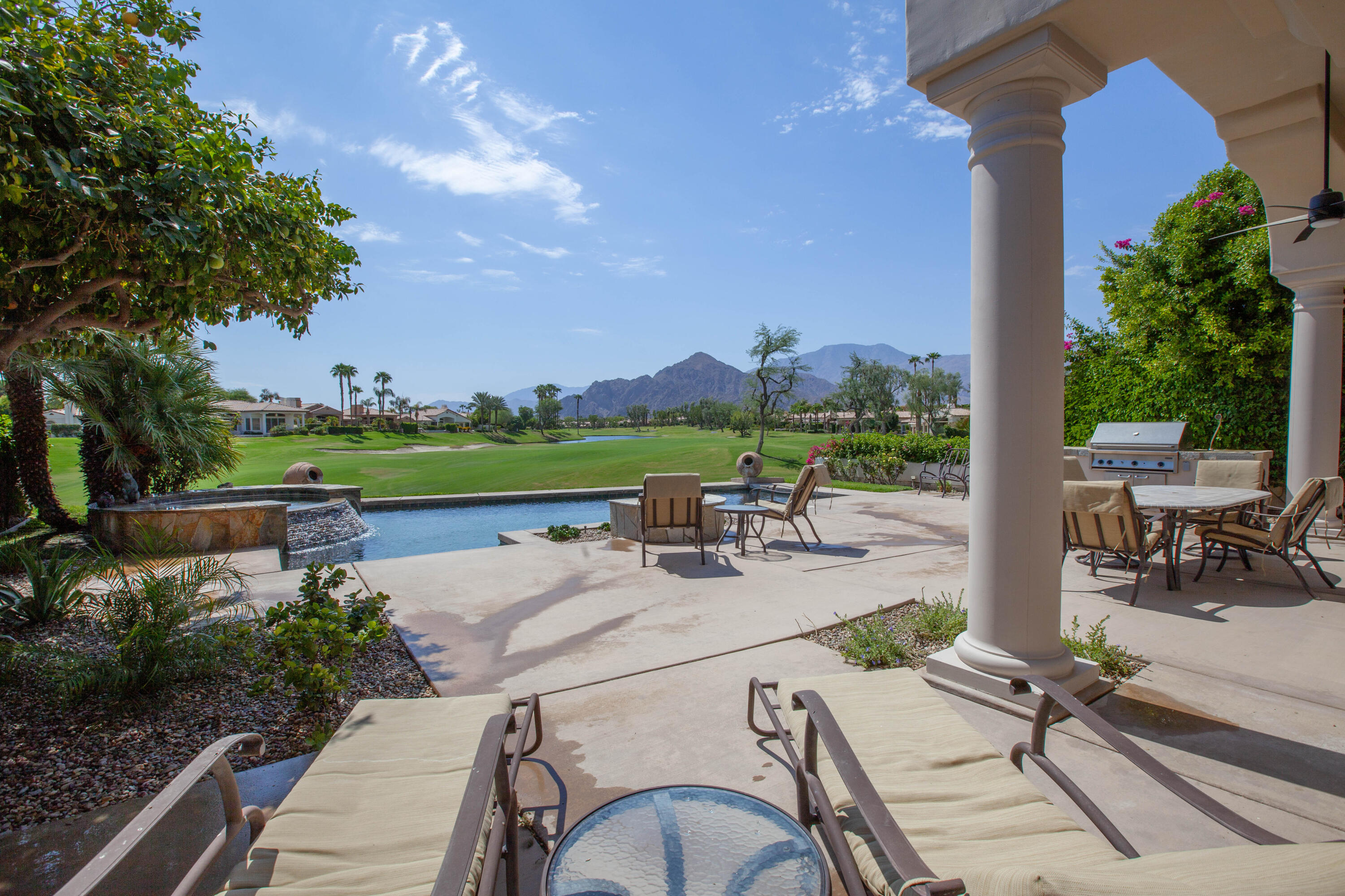 a view of a patio with chairs and table with potted plants and big yard