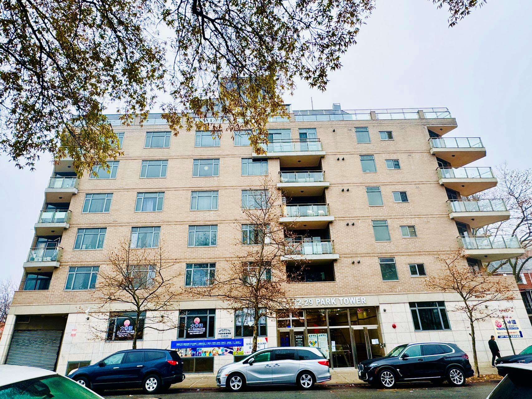 a front view of a building with lot of cars and trees