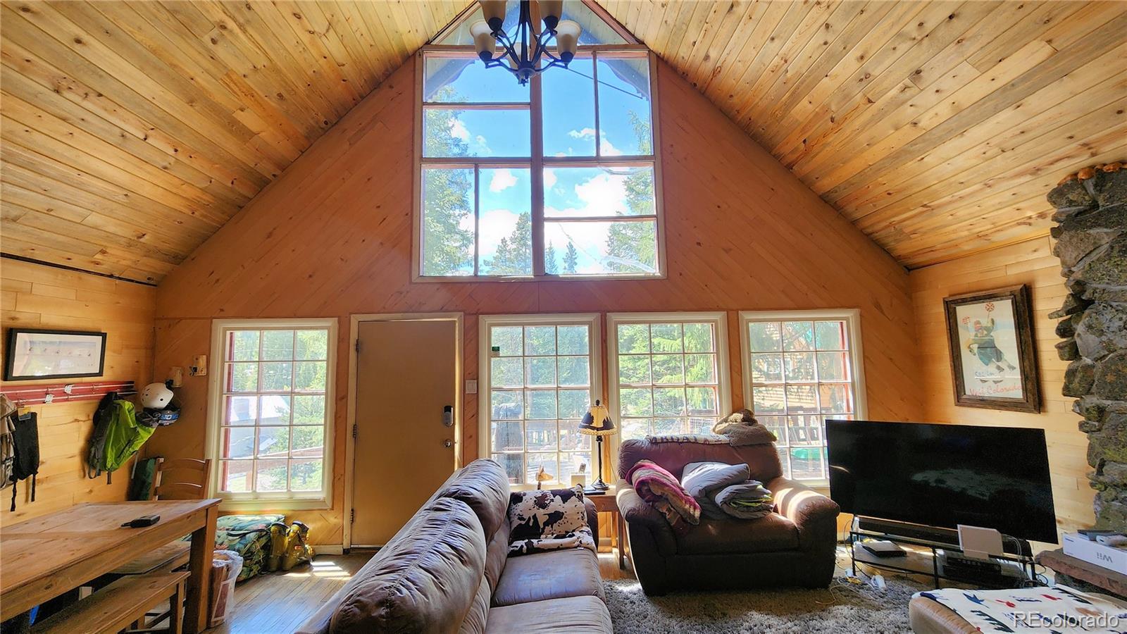 a living room with furniture a flat screen tv and floor to ceiling window