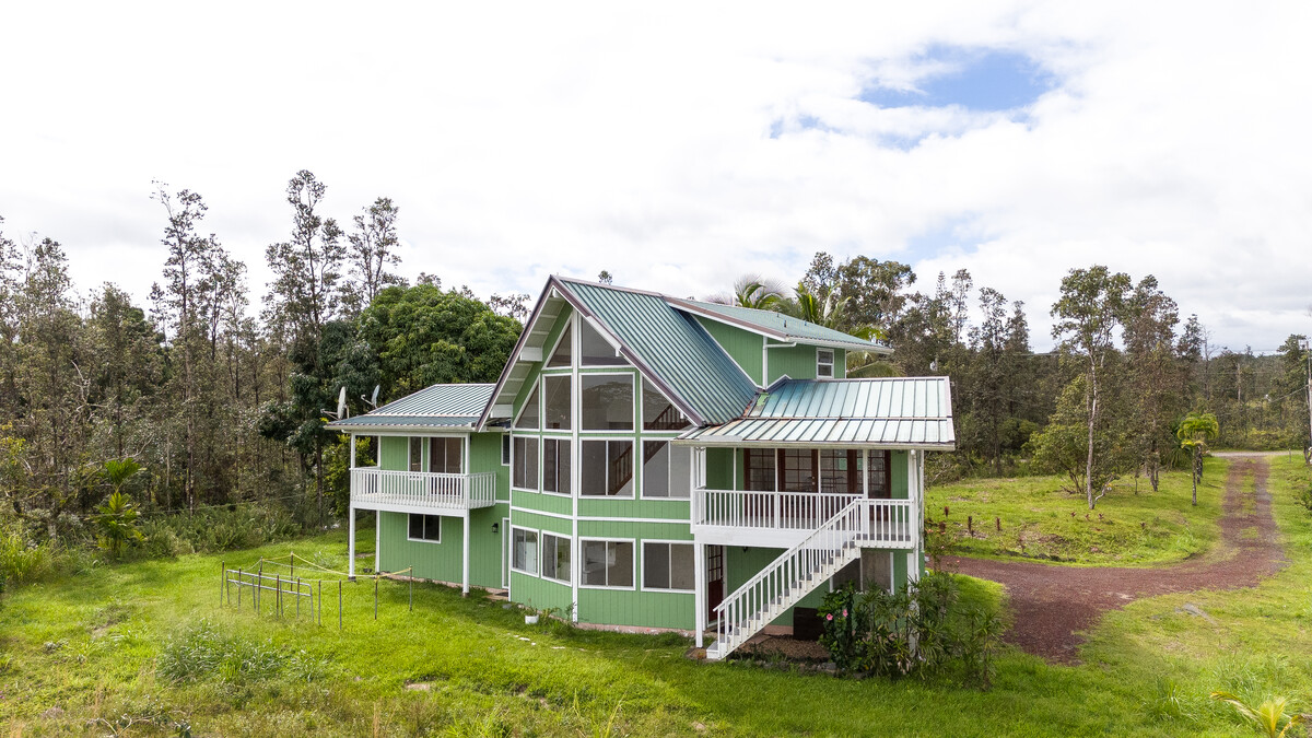 a view of a house with a big yard and large trees