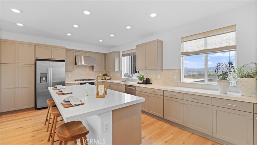 a kitchen with stainless steel appliances kitchen island granite countertop a table chairs sink and cabinets