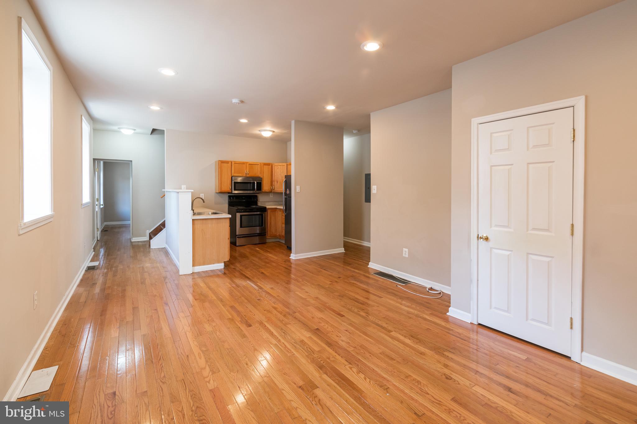 a view of a big room with wooden floor and a kitchen