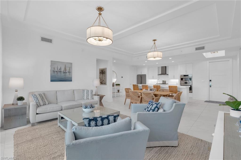 a living room with furniture kitchen view and a chandelier