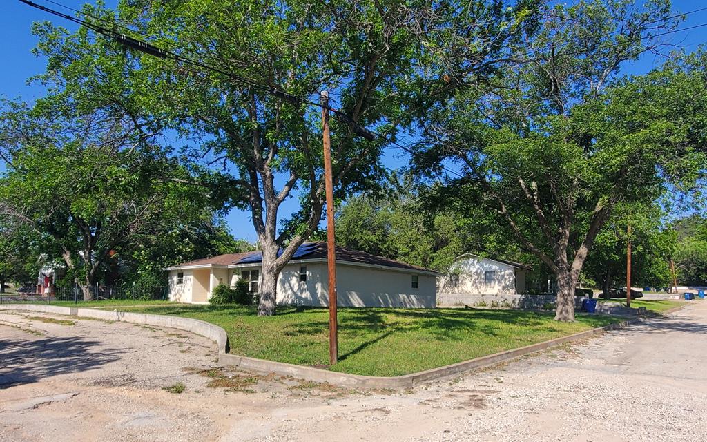 a front view of a house with a yard and tree s