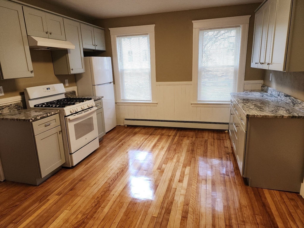 a kitchen with wooden floors and white appliances