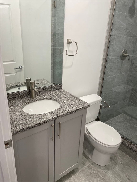 a bathroom with a granite countertop toilet a sink and a mirror