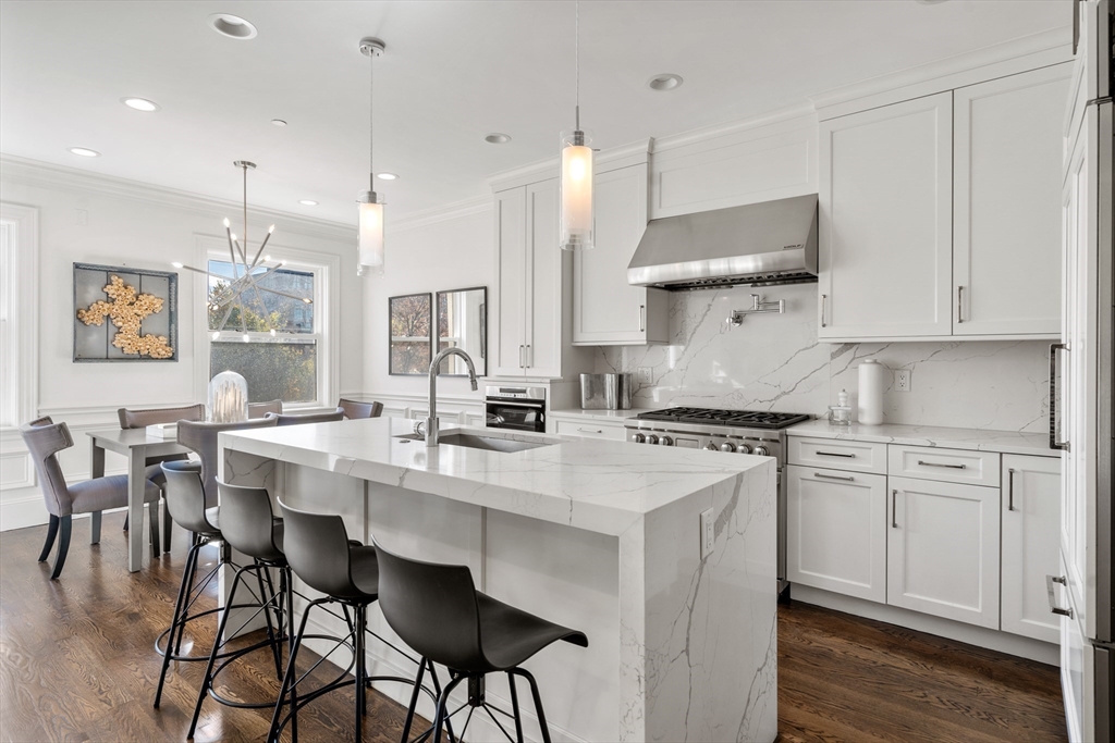 a kitchen with stainless steel appliances a table chairs refrigerator and sink