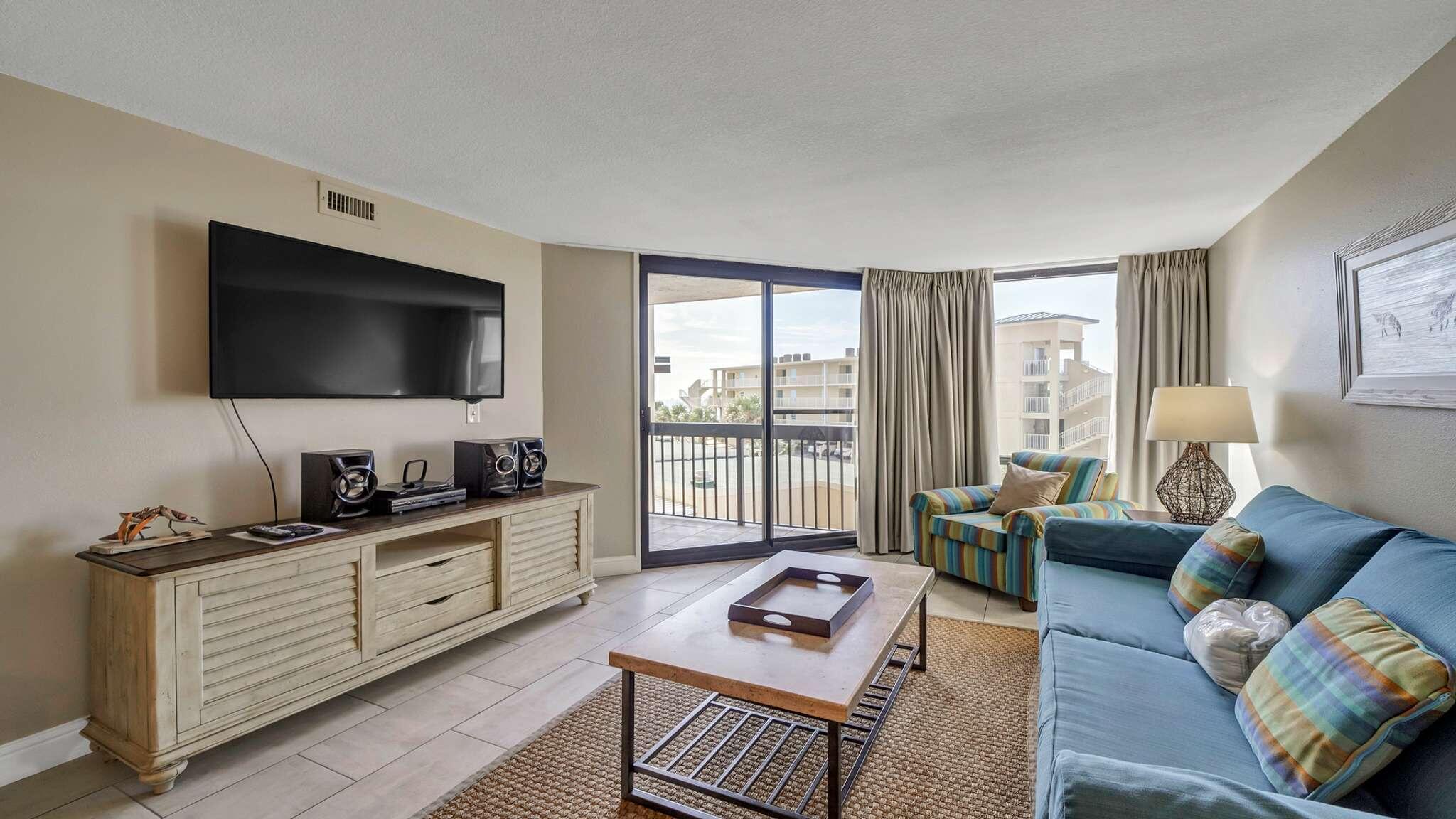 a living room with furniture a flat screen tv and a floor to ceiling window