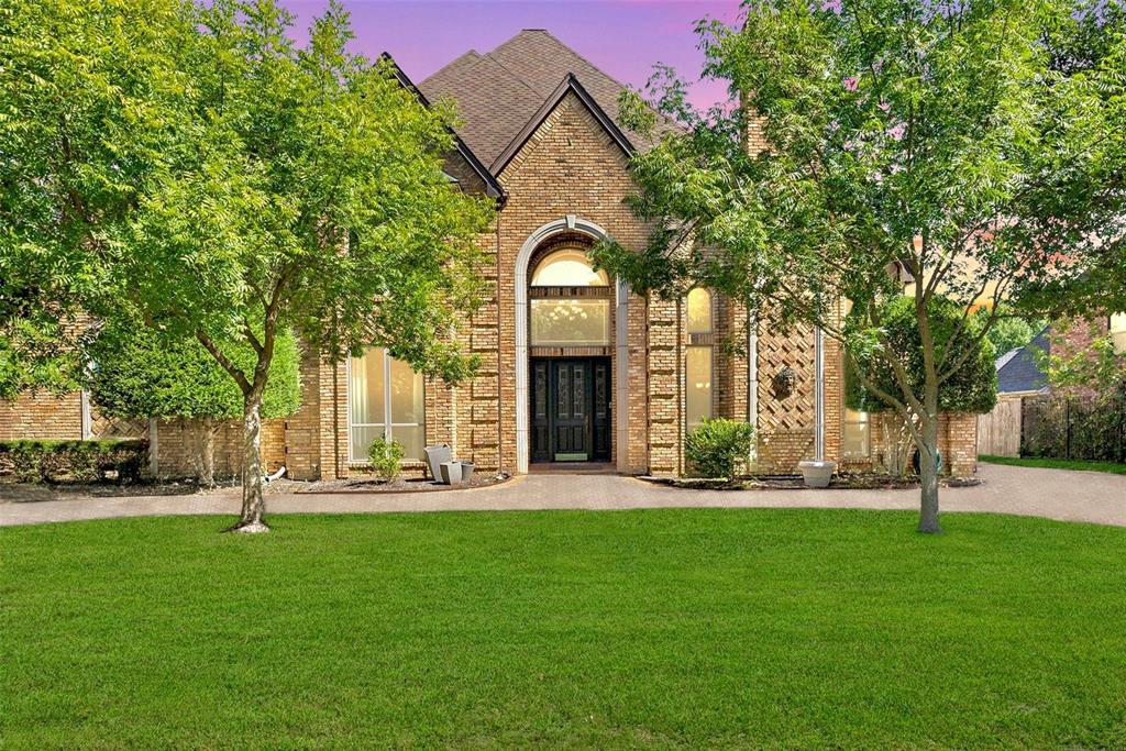 a front view of a house with a garden and trees