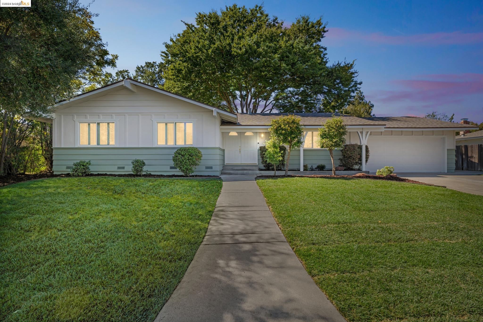 a front view of a house with a yard and trees