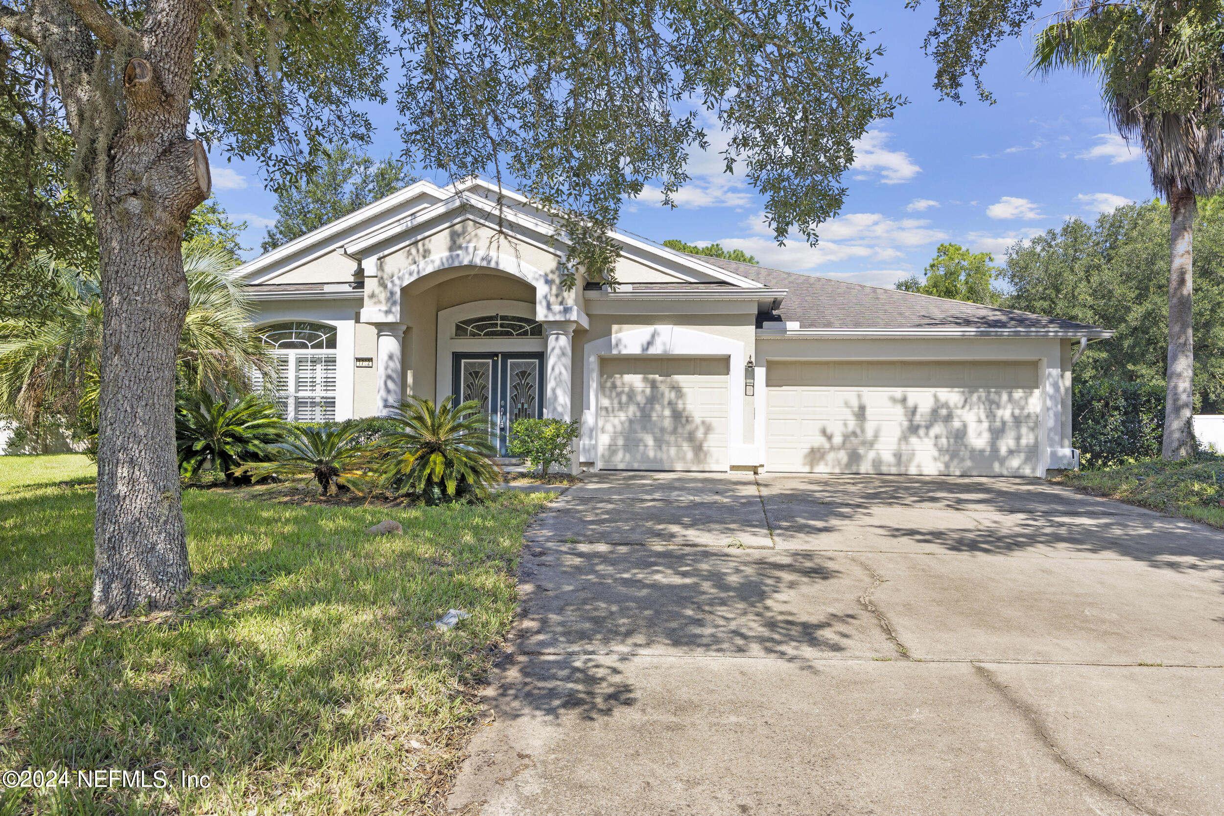 a front view of a house with a garden and trees