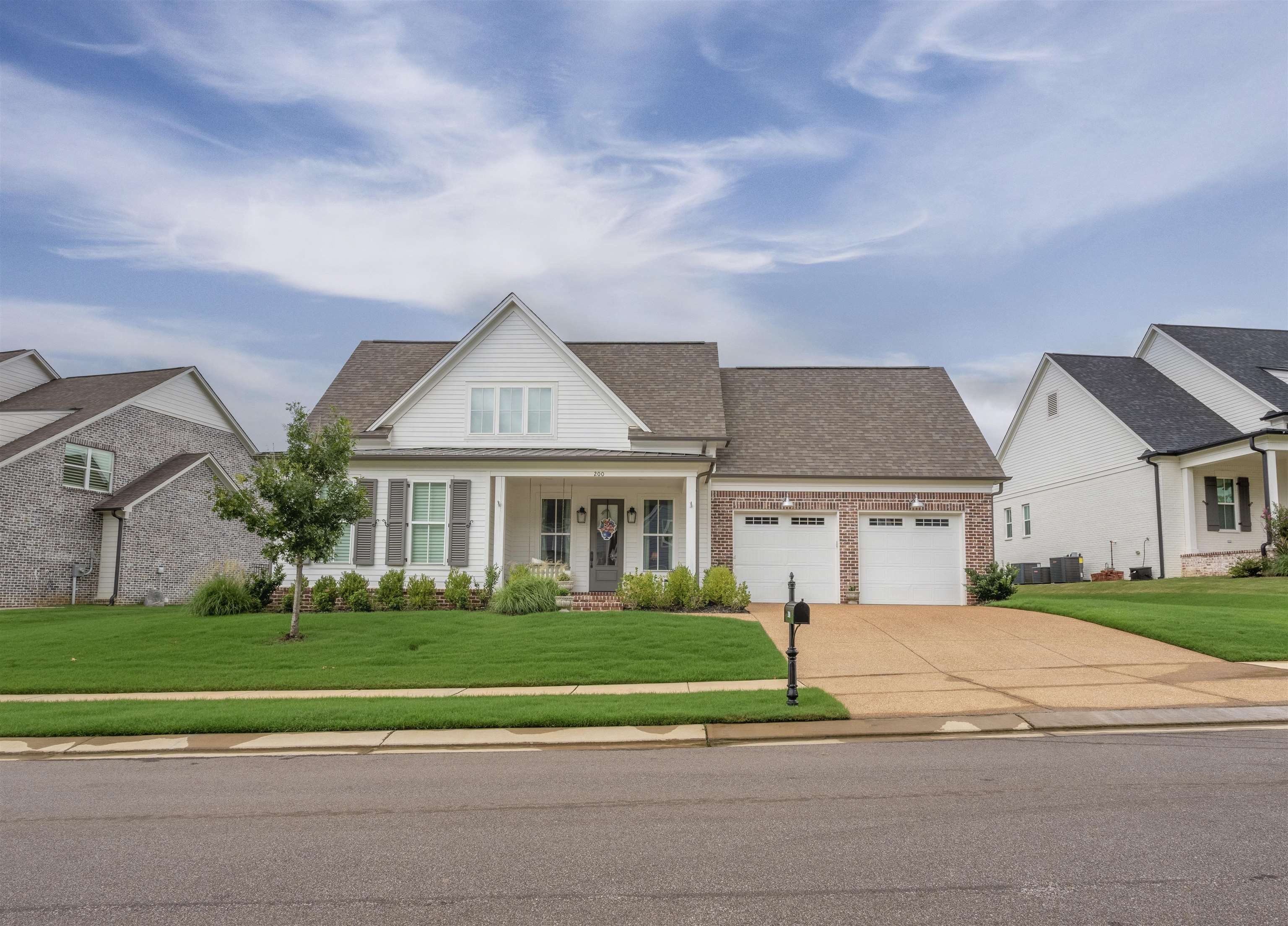 View of front of house with a porch, a garage, central AC, and a front yard