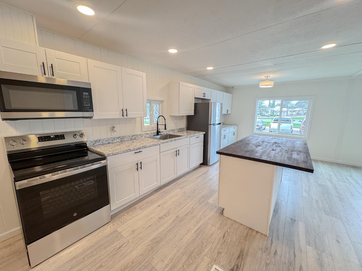 a kitchen with granite countertop wooden floors appliances and sink