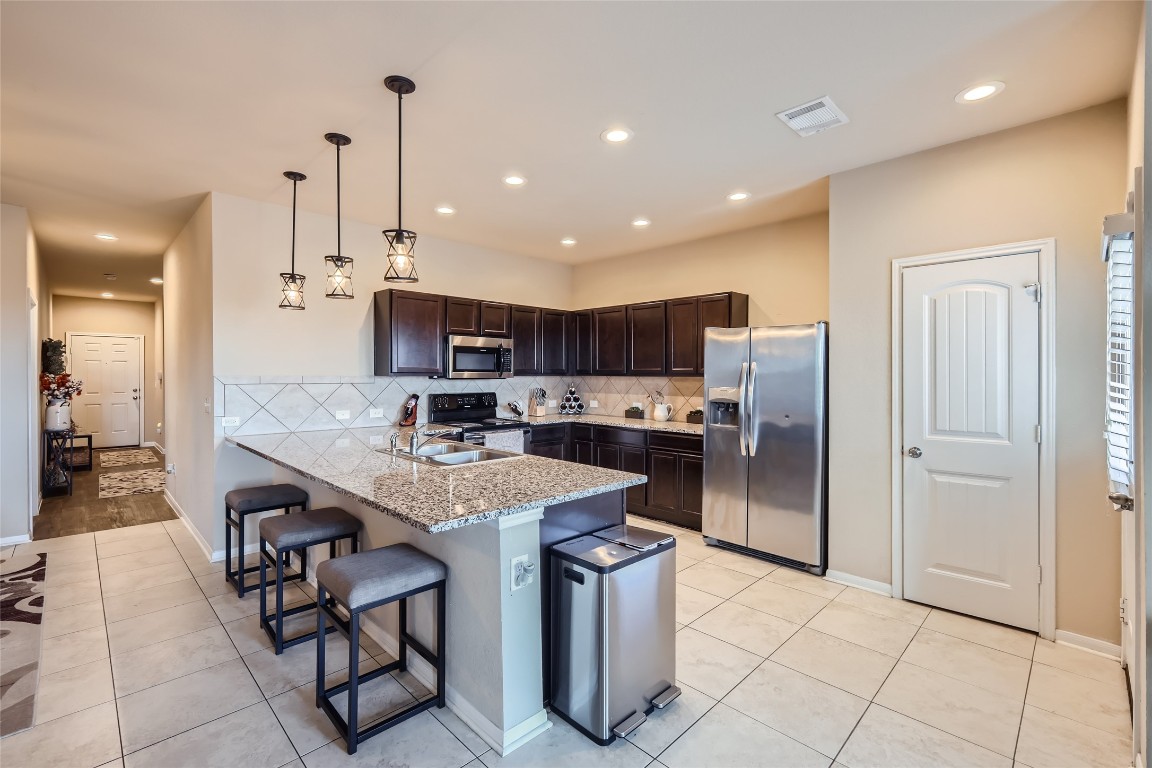 a kitchen with stainless steel appliances granite countertop a table chairs sink and cabinets