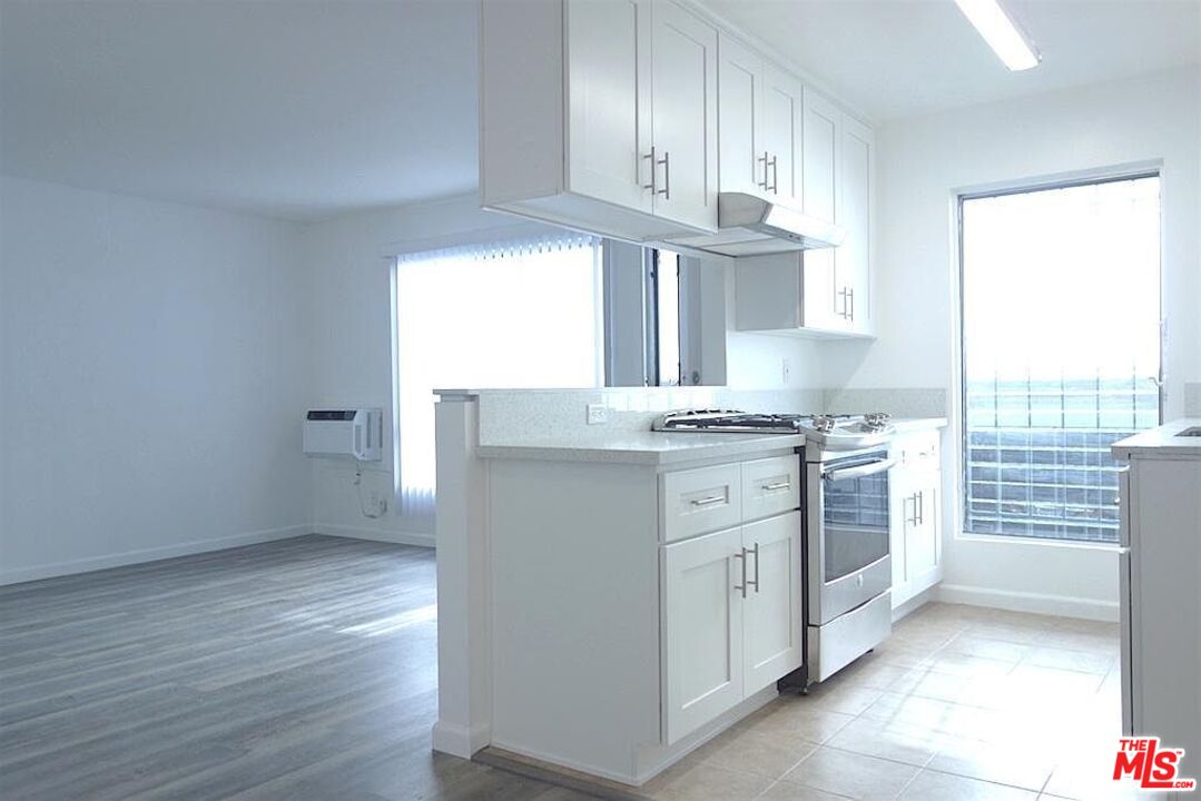 a kitchen with granite countertop a sink cabinets stainless steel appliances and a window