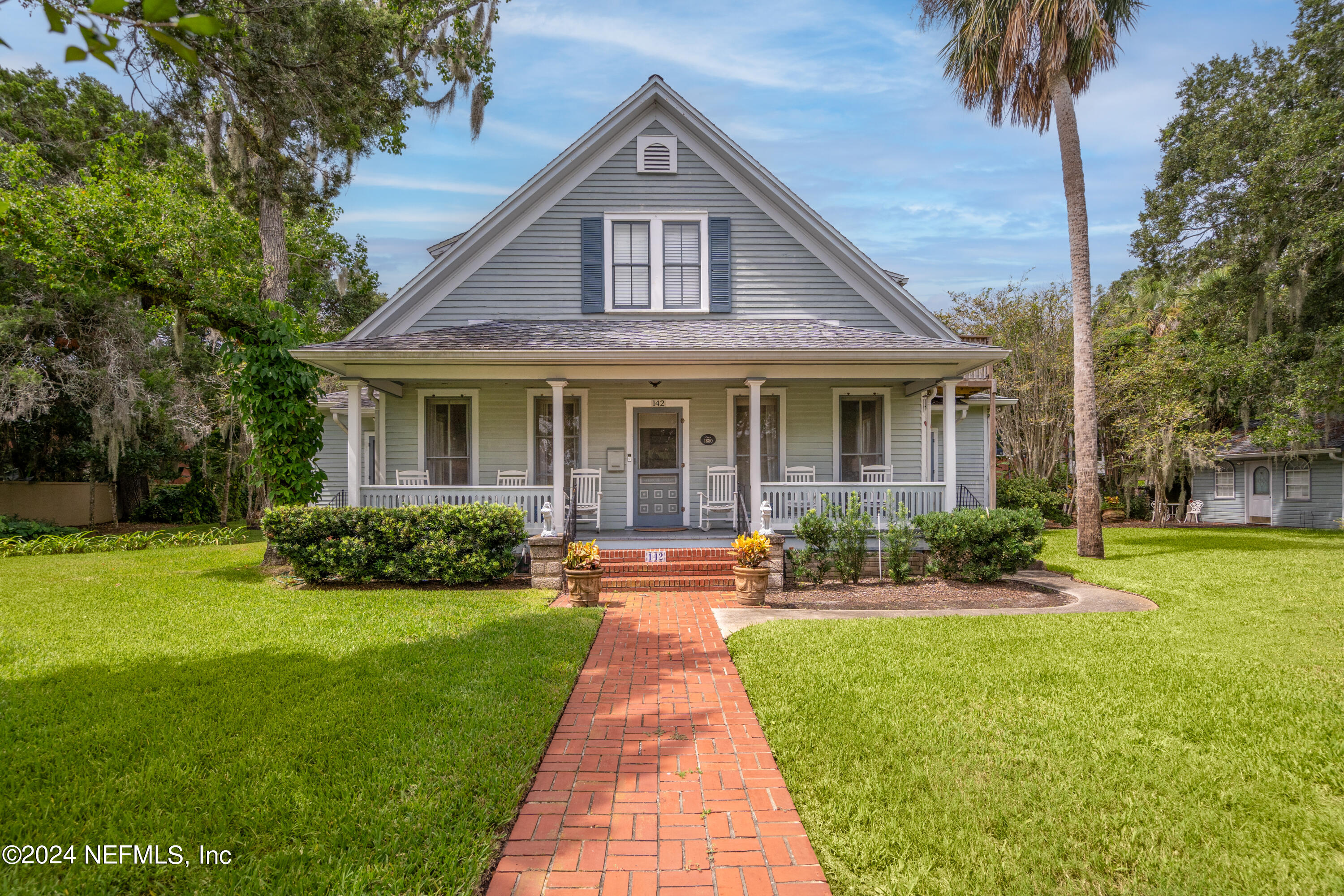 a front view of a house with a yard and potted plants