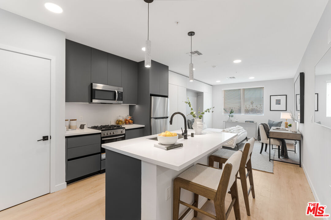 a kitchen with a dining table chairs stainless steel appliances and cabinets