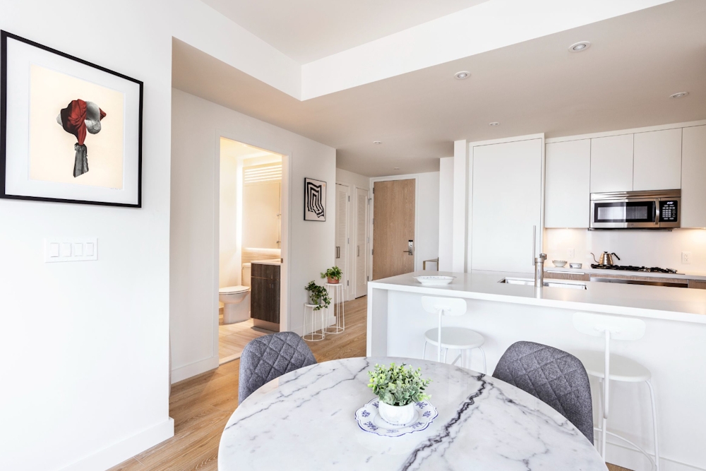 a living room with stainless steel appliances furniture a rug and a refrigerator