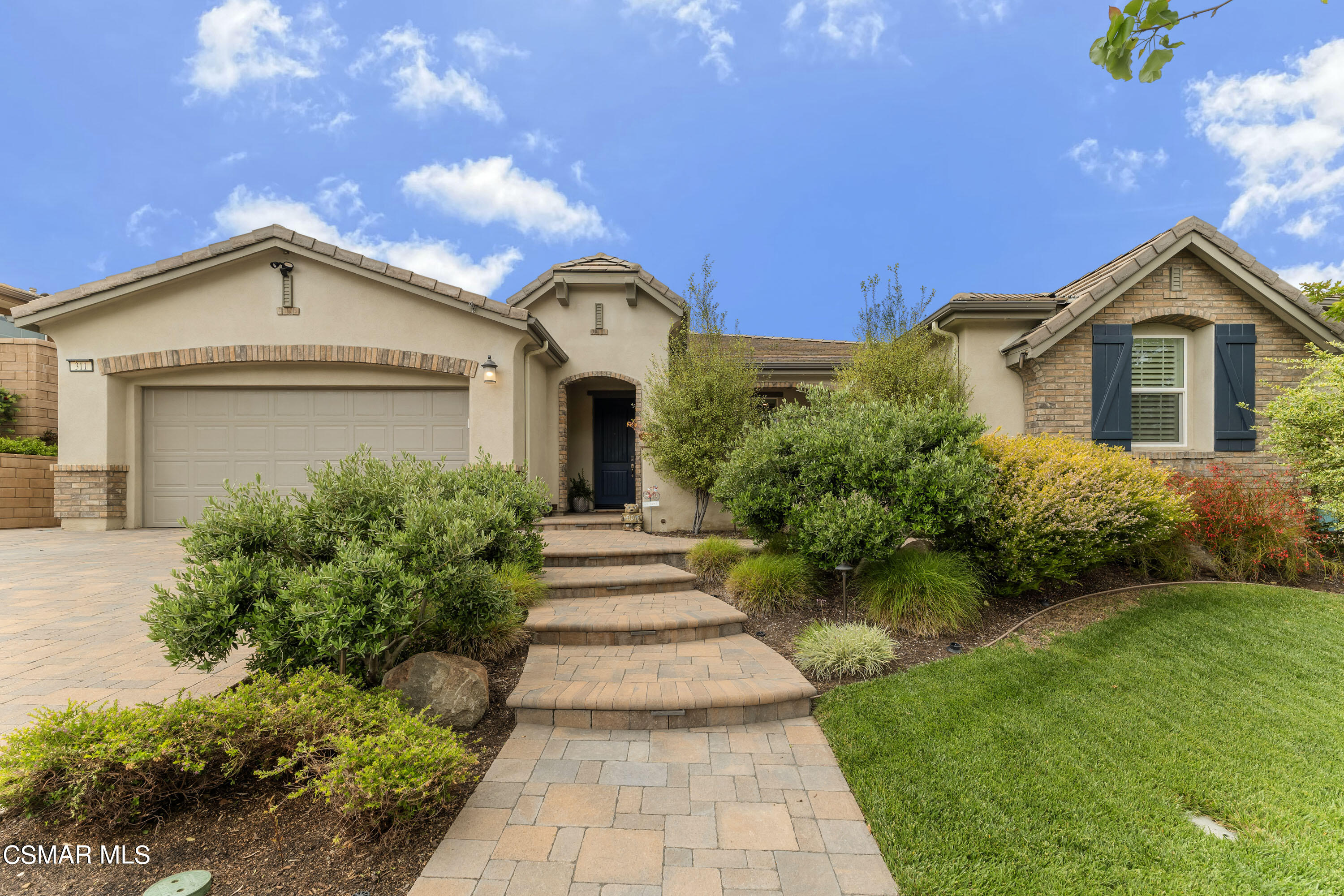 a front view of a house with a yard and potted plants