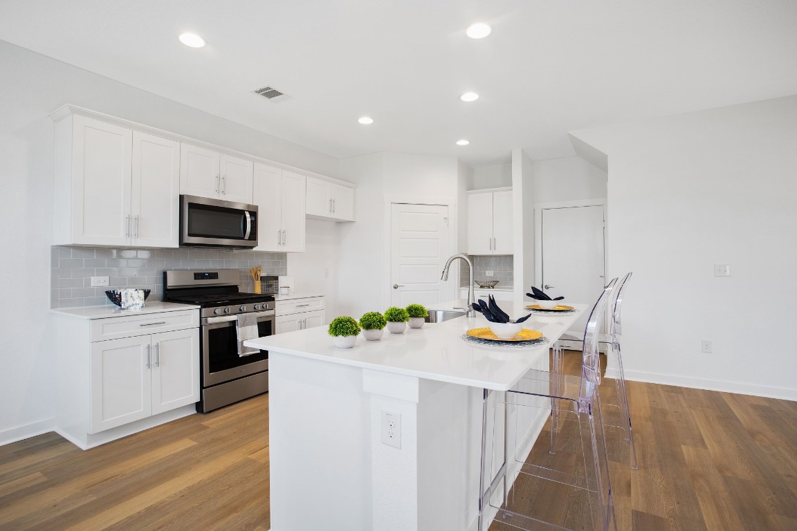 a kitchen with cabinets a stove and a wooden floor