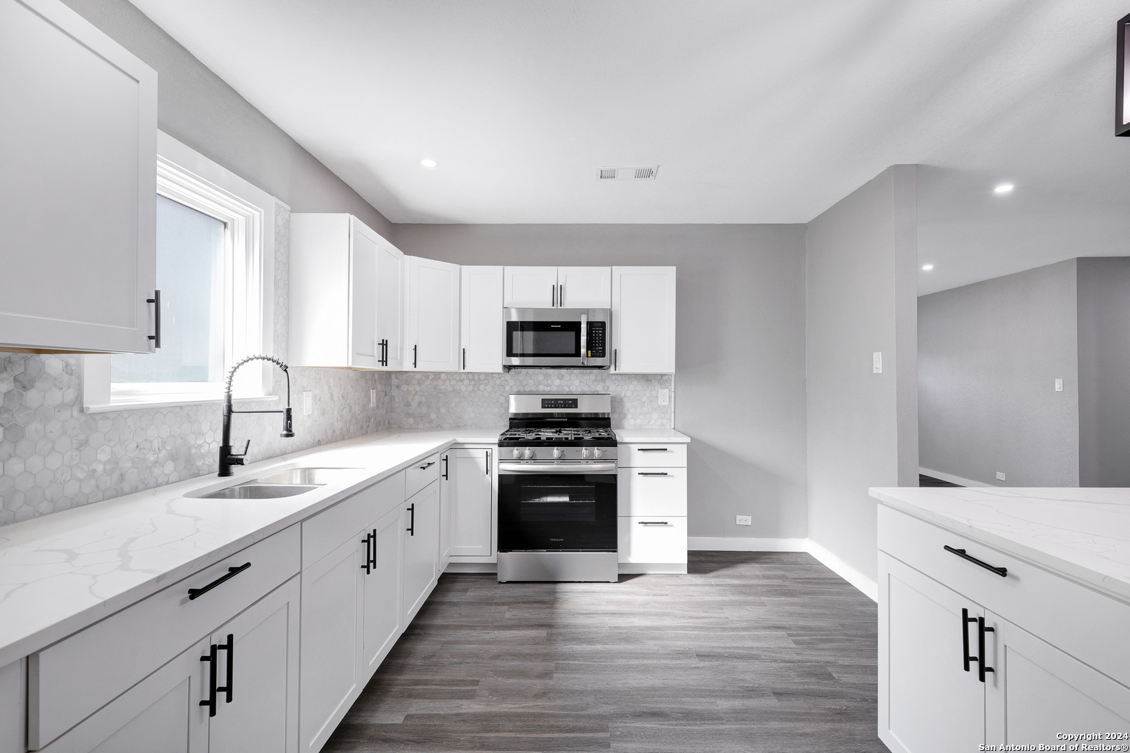 a kitchen with granite countertop white cabinets and stainless steel appliances