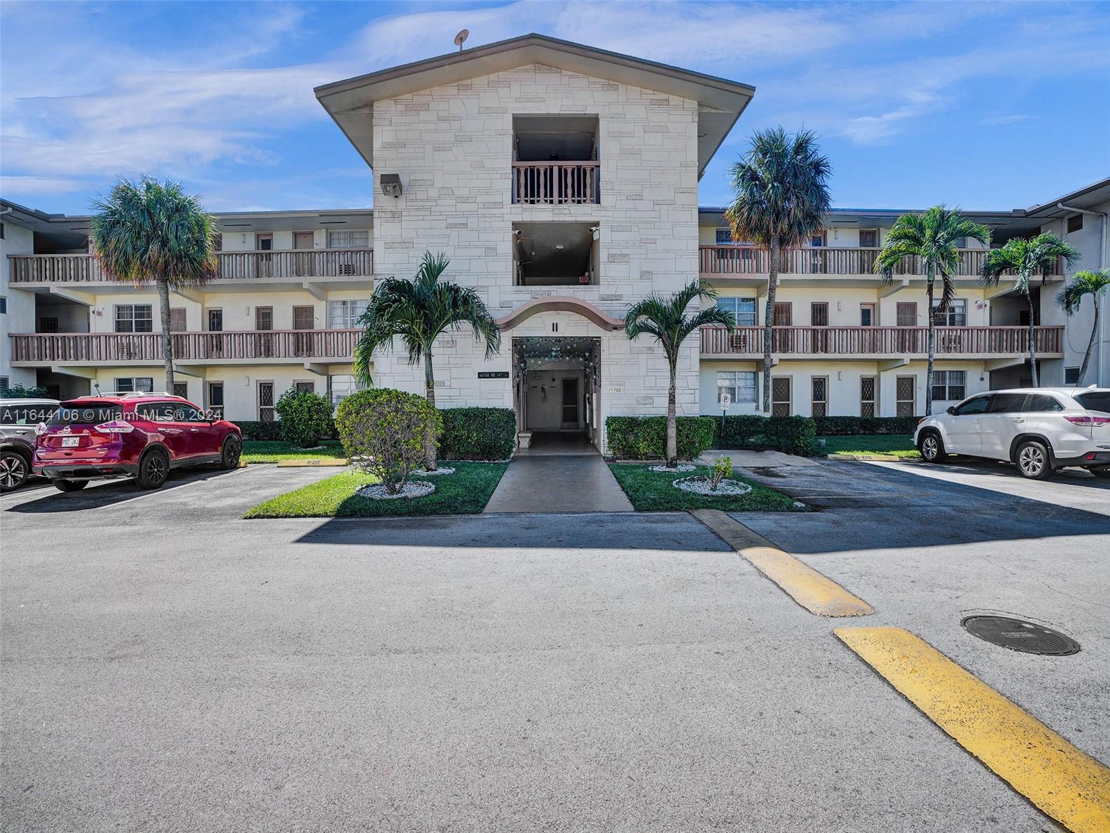 a front view of residential houses with yard and parking