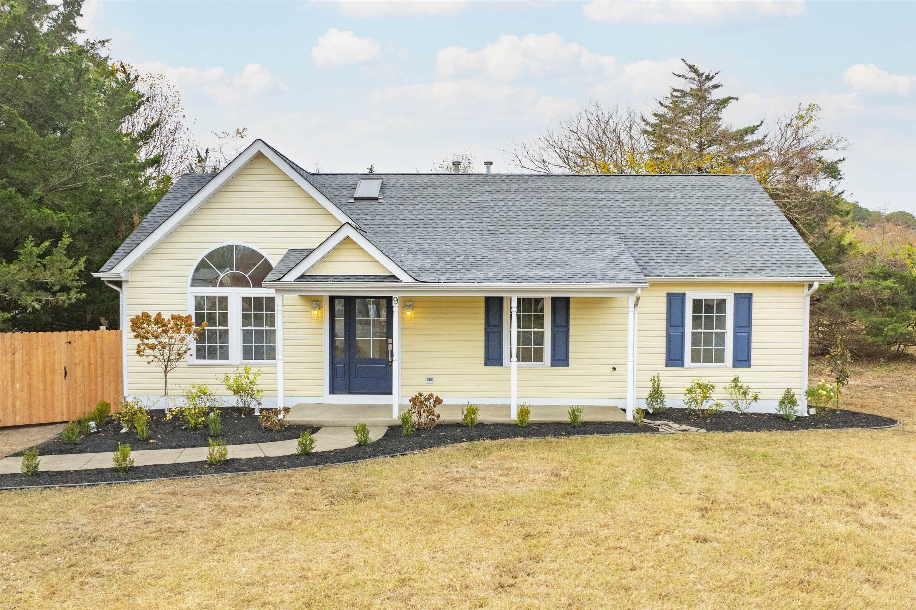 a front view of a house with yard and trees in the background