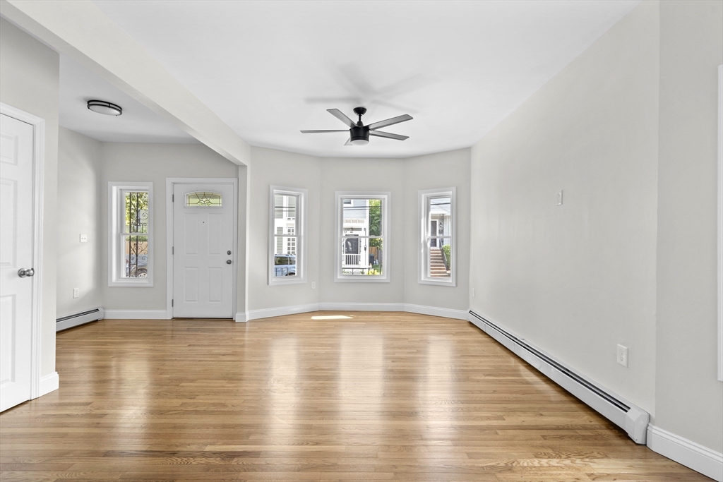 a view of an empty room with window and wooden floor