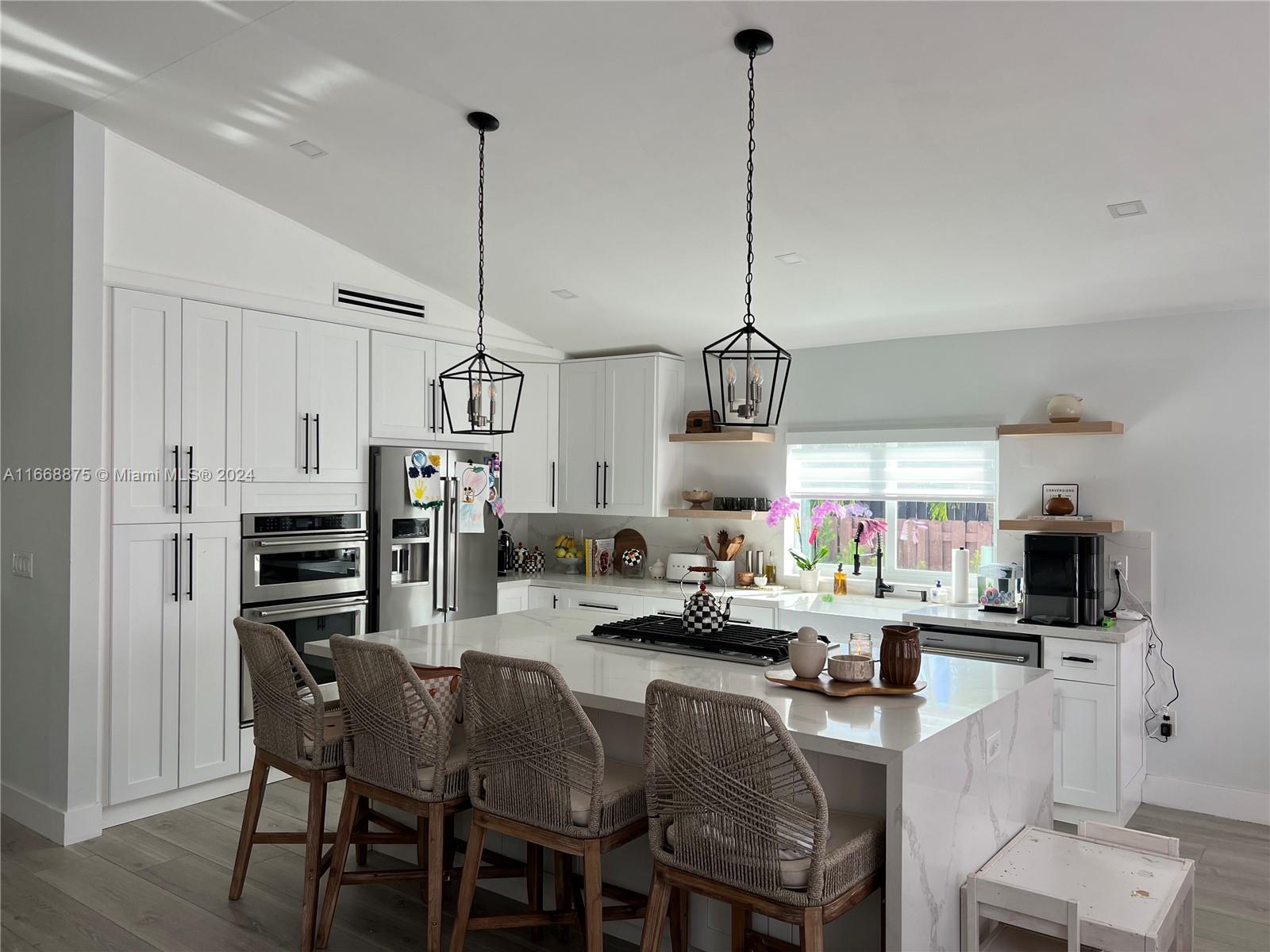 a kitchen island with stainless steel appliances kitchen island granite countertop a table chairs and a refrigerator