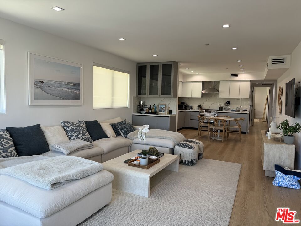 a living room with furniture kitchen view and a large window