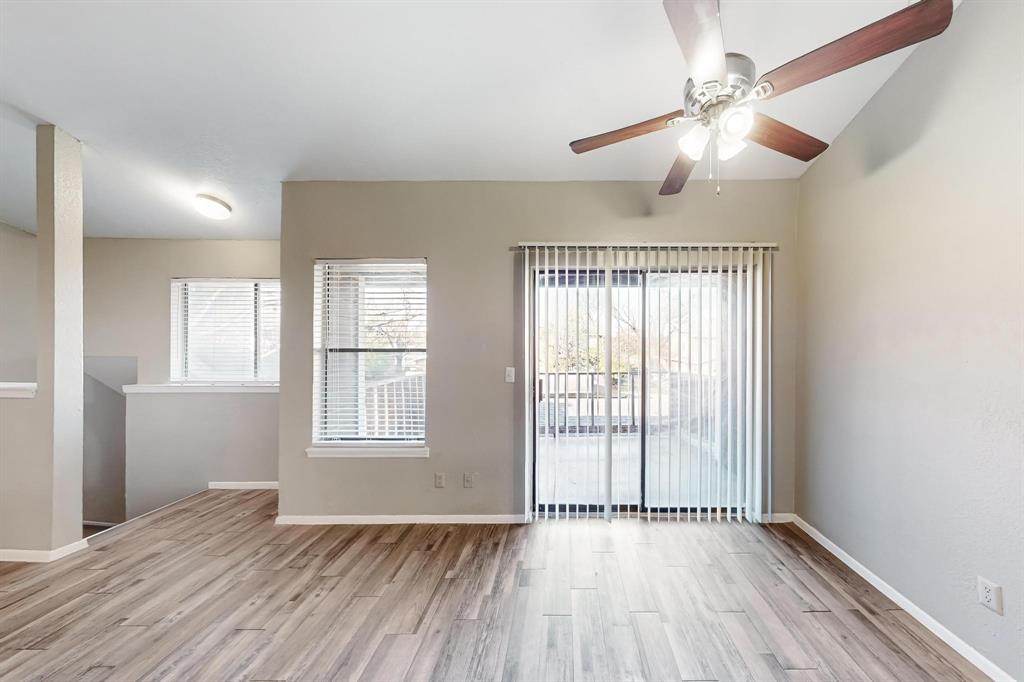 an empty room with wooden floor fan and windows