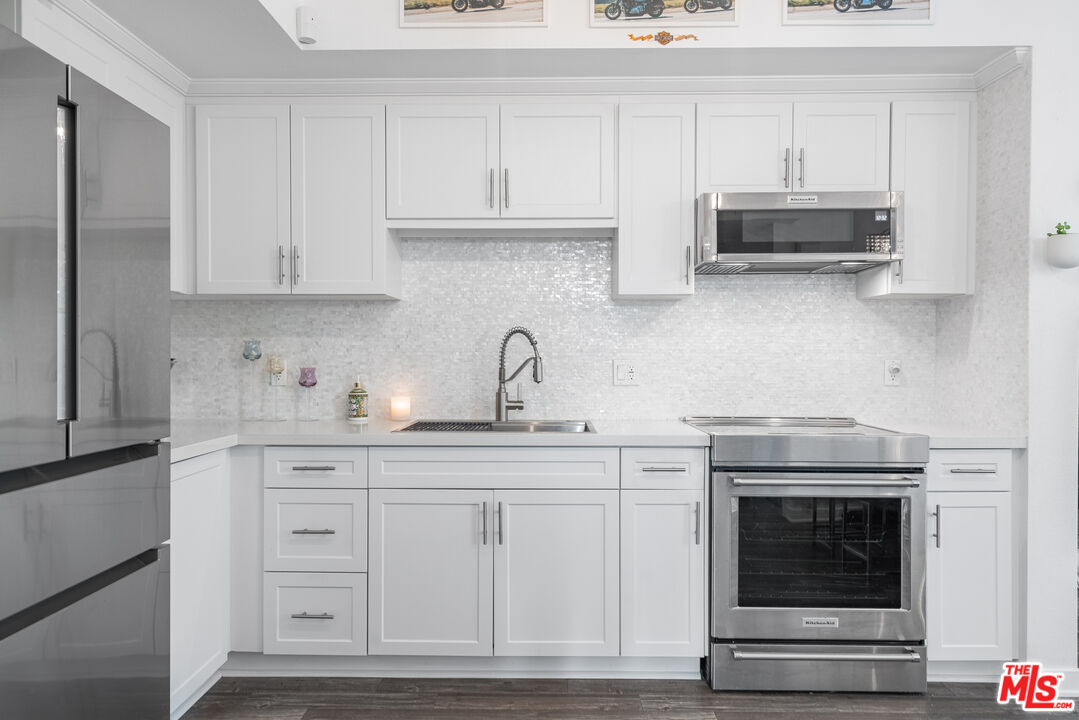 a kitchen with granite countertop white cabinets and stainless steel appliances