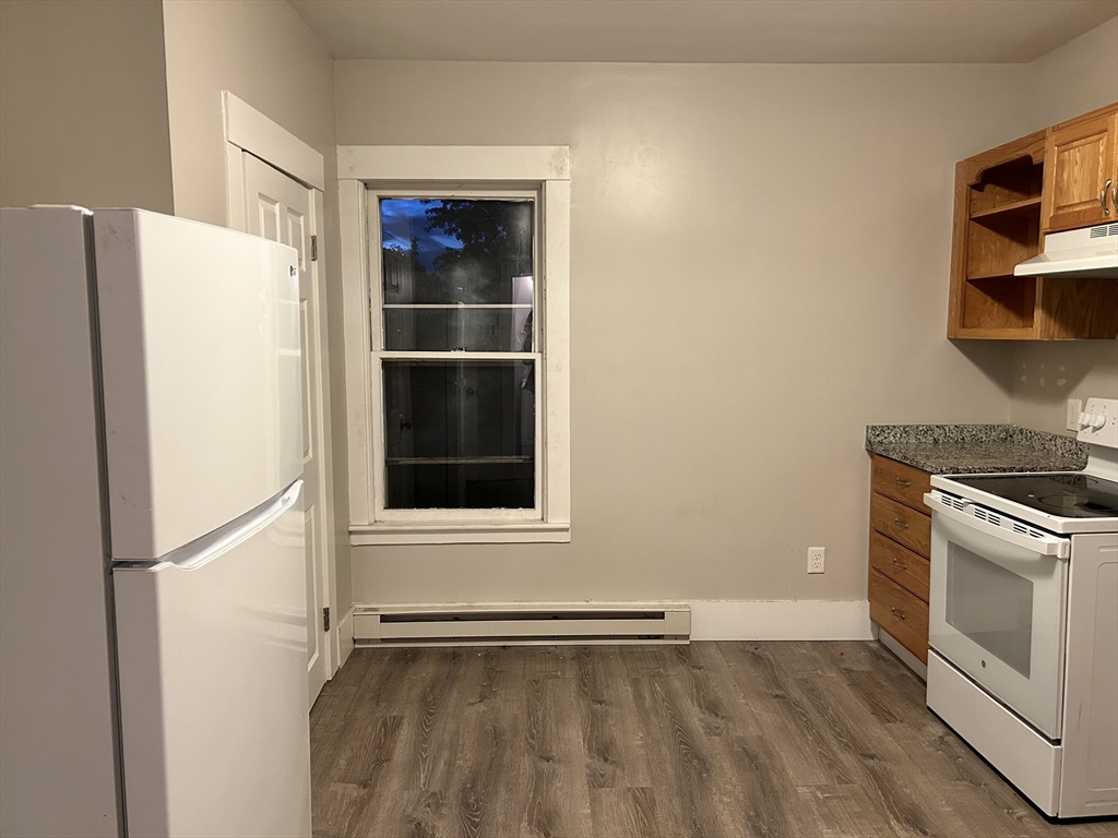 a view of an empty room with a kitchen and a window