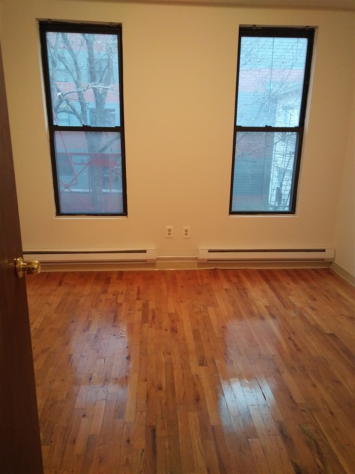 a view of an empty room with a window and wooden floor