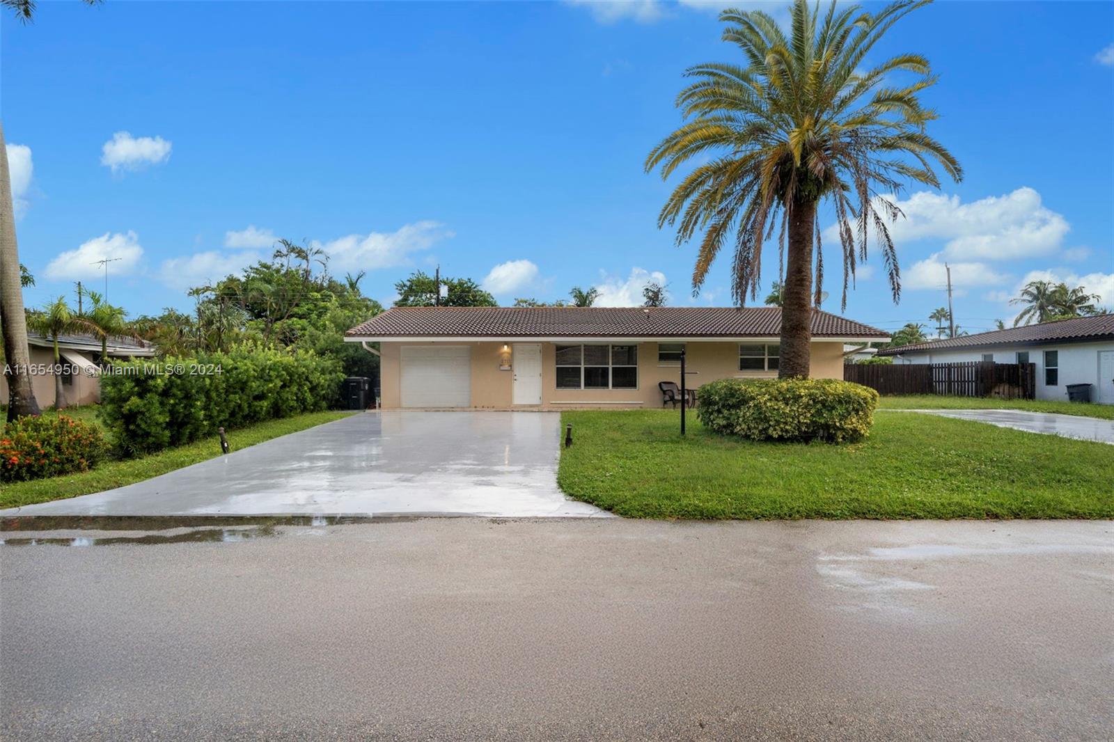 front view of house with a yard and palm trees