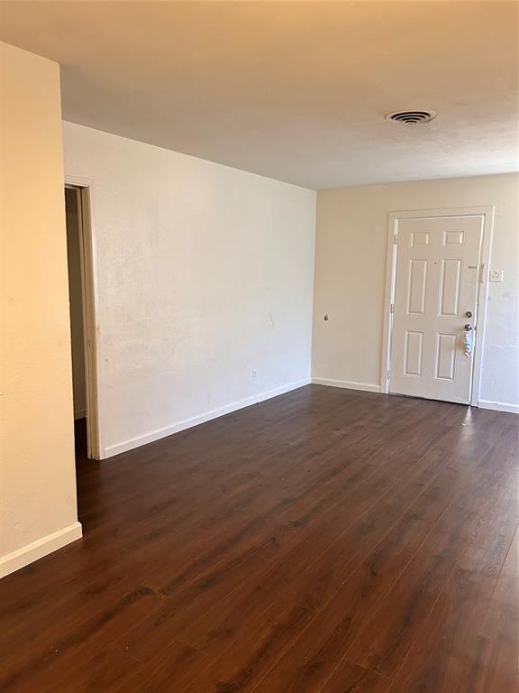 a view of an empty room with wooden floor