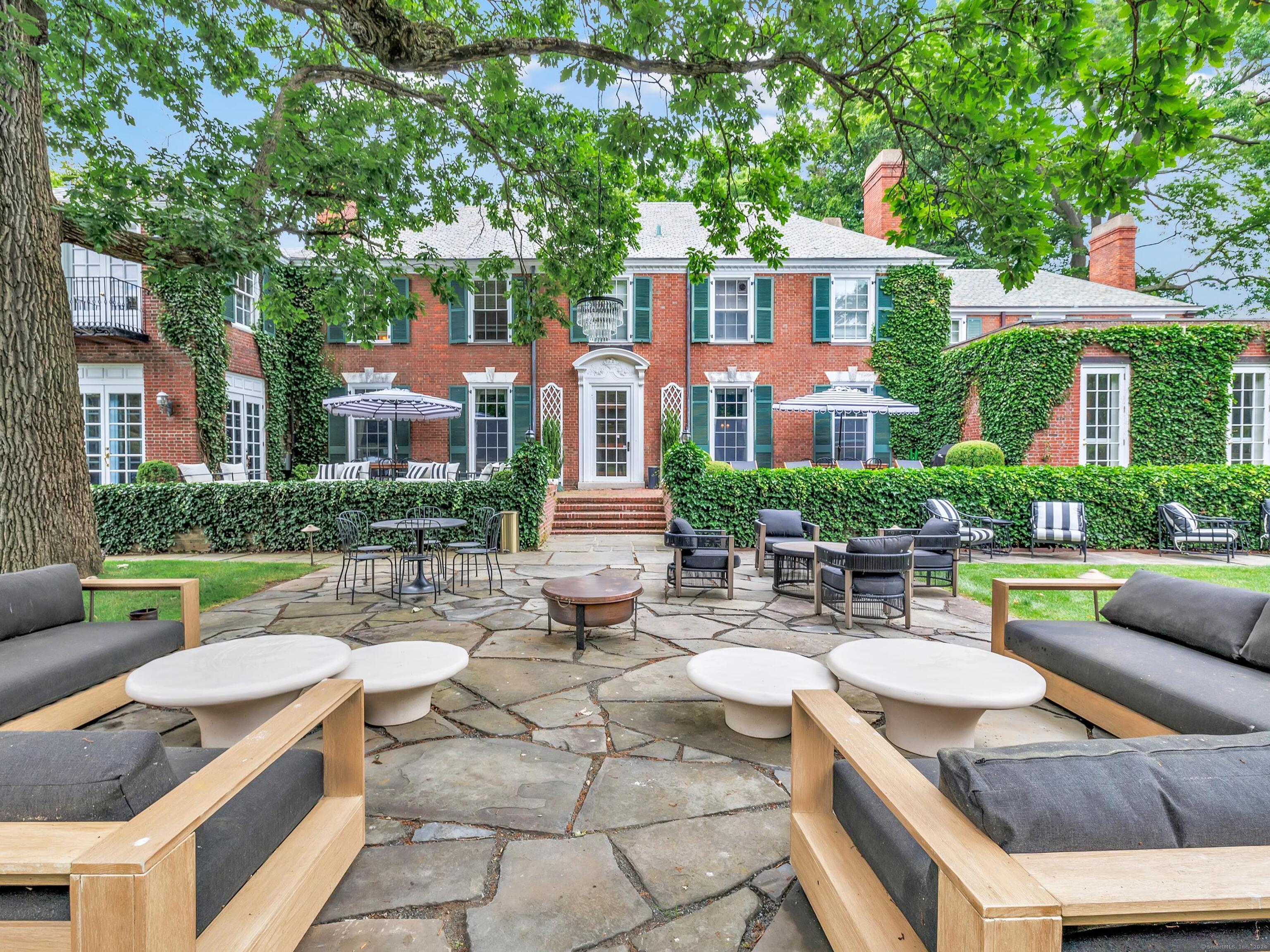 a view of a patio with couches table and chairs with plants and trees